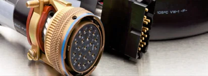 Connettore circolare multipolare dorato e connettore rettangolare, in primo piano